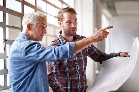 That walll needs to go. Shot of two male architects holding blueprints inspecting a building.