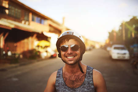 Theres nothing more enjoyable than a ride on your bike. Shot of a young man taking a drive through the city on his scooter.の写真素材