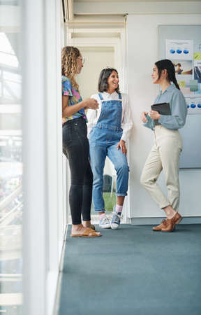 Catching up while making big plans. Shot of a group of businesswomen having a discussion in an office.の写真素材