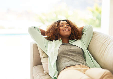 The weekends are for napping. Cropped shot of an attractive young woman resting on her sofa at home.の写真素材