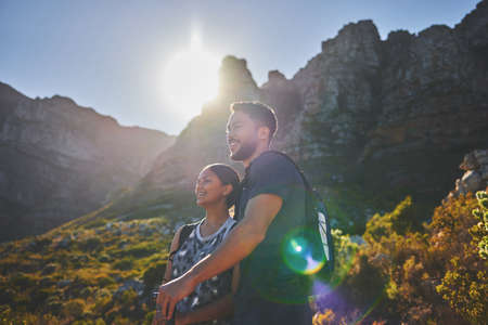 Hiking trails and sunny days. Shot of a young couple hiking on a mountain range outdoors.の写真素材