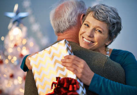 Christmas hugs are their own gift. Shot of a mature woman giving her partner a hug to thank him for her gift.の写真素材