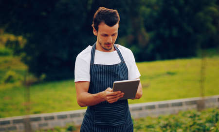 Got a green thumb Theres an app for that. Shot of a young man using a digital tablet while working in a garden.の写真素材