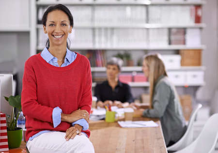 Shes a valued member of the team. Portrait of a confident young businesswoman with her colleagues working in the background.の写真素材