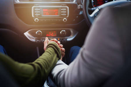 Life is a journey best travelled together. Closeup shot of a couple holding hands while driving in a...