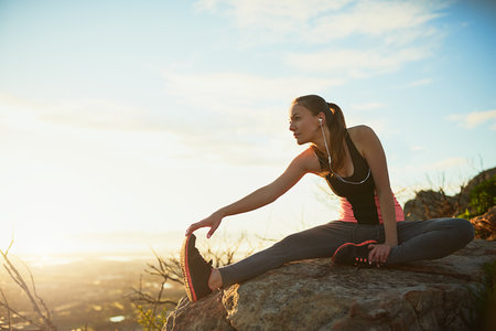 Warming up with a view. Shot of a sporty young woman stretching outdoors.