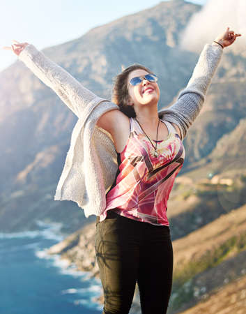 Feeling free in the great outdoors. Cropped shot of a teenage girl standing with her arms raised outdoors.の写真素材