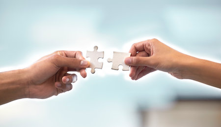 I bring the idea, she executes it. Cropped shot of two unrecognizable businesspeople holding up two puzzle pieces in the office.の写真素材