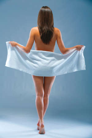 Give your body a fresh start. Rearview shot of a topless woman covering her behind with a towel.の写真素材