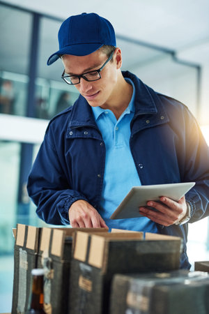 Double checking all his deliveries. Shot of a courier using a digital tablet while sorting through...