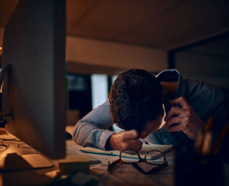 When bad news comes calling. Shot of a young businessman looking stressed out while talking on a cellphone in an office.の写真素材
