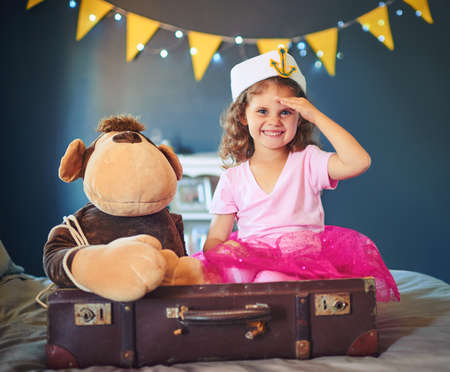 Ahoy. Portrait of an adorable little girl dressed up as a sailor and playing on the bed at home.の写真素材