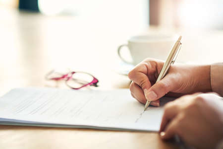 Sign on the dotted line. Cropped shot of an unrecognizable businesswoman filling in paperwork in an...