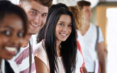 She loves university life. Portrait of a beautiful young college student standing with her friends.