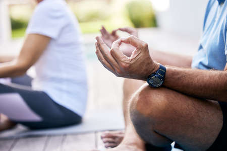 Yoga will allow you to find clarity in your life. Closeup shot of an unrecognisable couple meditating outdoors.の写真素材
