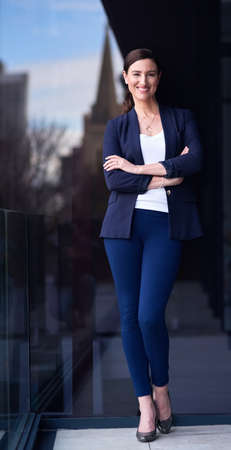 It feels good to be in charge. Portrait of a happy businesswoman standing on a balcony with her arms crossed.の写真素材