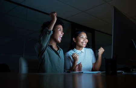 Our actions decide whether we sink or fly. Shot of two young businesswomen cheering while using a...