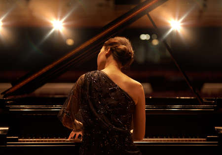 Performing for the audience. Shot of a young woman playing the piano during a musical concert.の写真素材