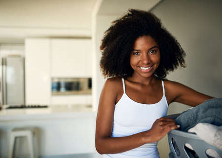 Time to do my daily chores. Cropped shot of an attractive young woman doing the laundry at home.の写真素材