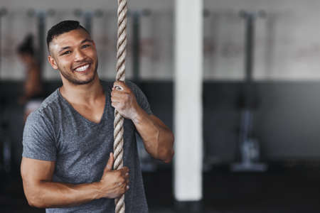 Im ready to conquer the rope. Cropped portrait of a young man climbing a rope at the gym.