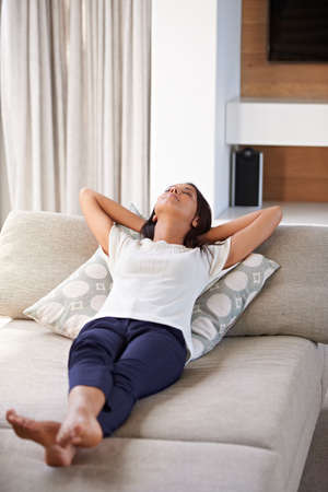 Blissful weekend moments. Shot of an attractive young woman lying with her hands behind her head on...