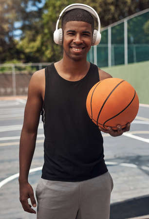 Wanna shoot some hoop. Portrait of a sporty young man listening to music while playing basketball on...