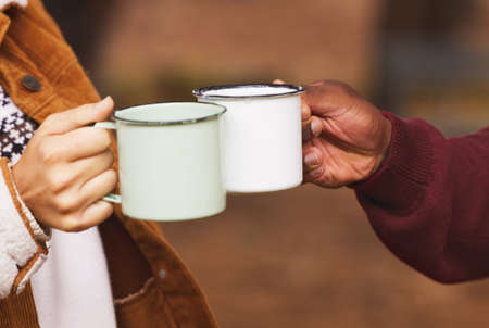 Lets get warmed up. Cropped shot of a couple sharing a toast with their coffee mugs while out in the wilderness.の写真素材