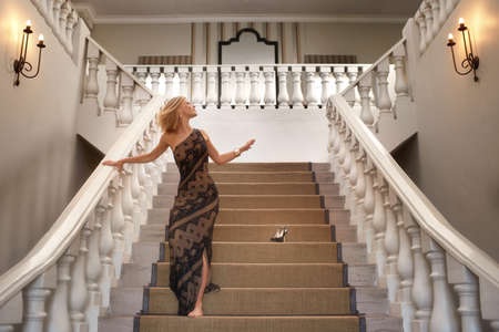Casual elegance. A young woman losing a shoe while running down a magnificent staircase.の写真素材