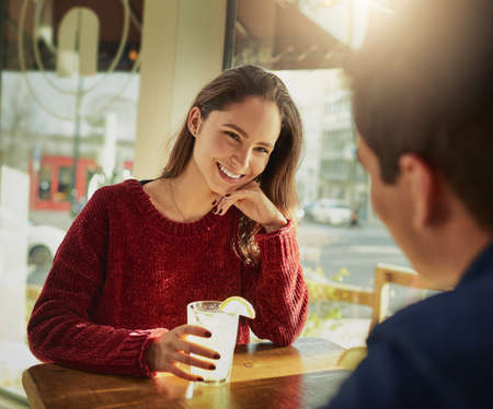 Hes every bit as handsome as his profile pic. Shot of a young man and woman on a romantic date at a coffee shop.の写真素材