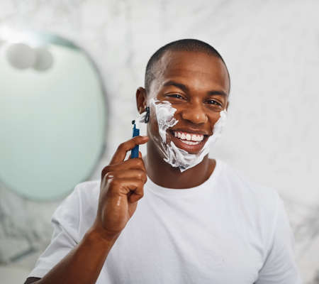 No whiskers for me. Portrait of a handsome young man shaving his facial hair in the bathroom.の写真素材