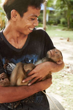 Monkey keeper- Thailand. A Thai macaque being held by his keeper.