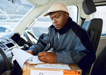 Lets get the day started. Shot of young man delivering a package while sitting in a vehicle.