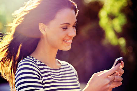 Happy connections. Shot of a beautiful young woman using a mobile phone in the outdoors.