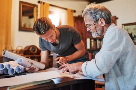Hes joining the family business. Shot of two men working on a project together at home.の写真素材