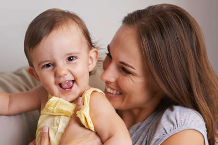 She makes me laugh all the time. Closeup portrait of a mother and baby daughter laughing.