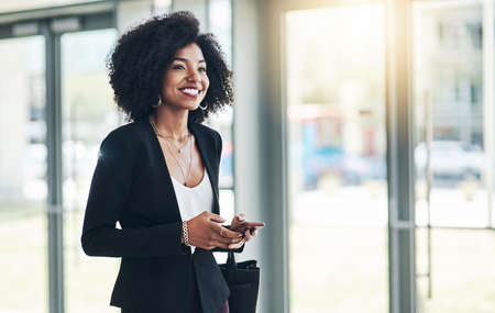 Im excited for this meeting. Shot of a confident young businesswoman texting on her phone while...