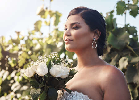 Theres nothing more beautiful than a woman on her wedding day. Cropped shot of a young bride posing outside with her bouquet.の写真素材