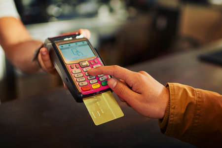 You may punch your pin in the machine. Closeup of an unrecognizable person paying their bill with a...