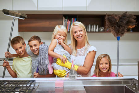 Moms got many helpers to keep their home sparkling clean. Portrait of a mother and her kids doing...