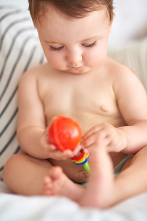 Hmmhow does this work. Cropped shot of an adorable baby girl playing with a toy.の写真素材
