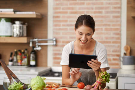 Looking for the perfect recipe online. Shot of an attractive young woman using her tablet in the...