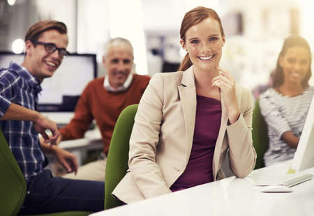 Theyre capable and successful. Portrait of a young office worker with colleagues in the background.
