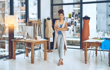 Turn your hobby to something that brings you funds. Portrait of a young fashion designer posing with her arms crossed in her workshop.の写真素材