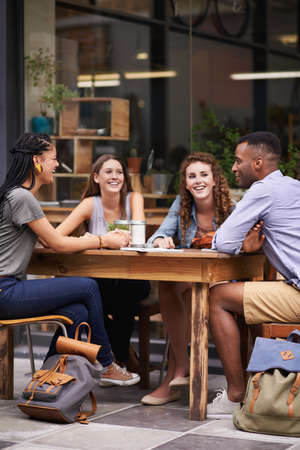 Nothing better than the company of friends. A group of young friends sitting outside at a sidewalk cafe.の写真素材
