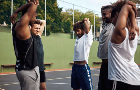 Got to warm up before we shoot some hoops. Shot of a group of sporty young men stretching their arms...