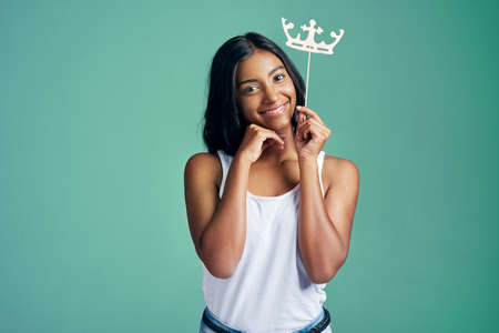 The cutest queen ever. Studio portrait of a beautiful young woman posing with a prop crown against a...