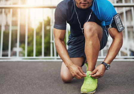 He lives for his daily run. Shot of a young man tying his shoelaces before a run.