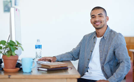 Portrait of a handsome young man working at his computer in an office. The commercial designs...