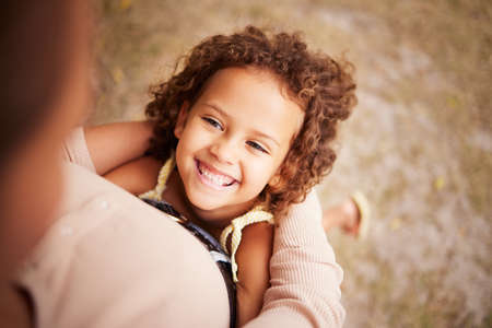 I like it when mom carries me around. Shot of a little girl holding onto her parent.の写真素材