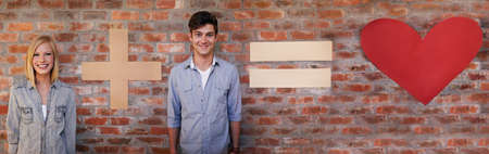 Mathematics of love. A young couple posing in front of a brick wall with a plus, equals and heart sign.の写真素材